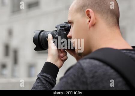 photography and hobby concept - close up back view of male photographer taking photo with modern dslr camera Stock Photo