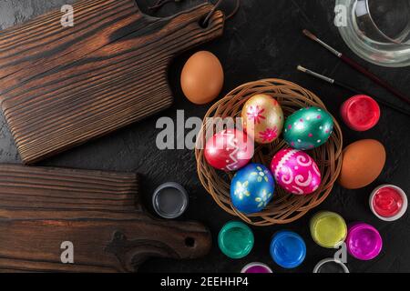 Multicolored easter painted handmade eggs, paints and brushes. Festive Easter frame from eggs, paints and brushes on black background with copy space Stock Photo