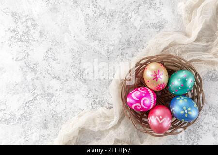 Five easter eggs trendy colored deep blue, green, orange, magenta and golden decorated in basket on white background. Copy space for text. Stock Photo