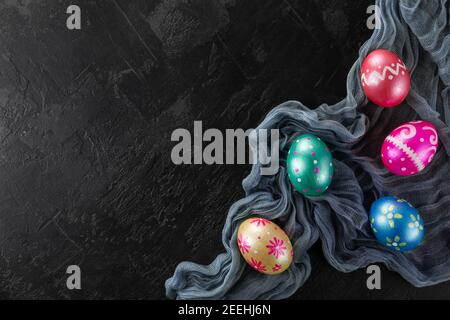 Easter eggs trendy colored classic deep blue, green, orange, magenta and golden decorated on black background. Happy Easter card with copy space for t Stock Photo