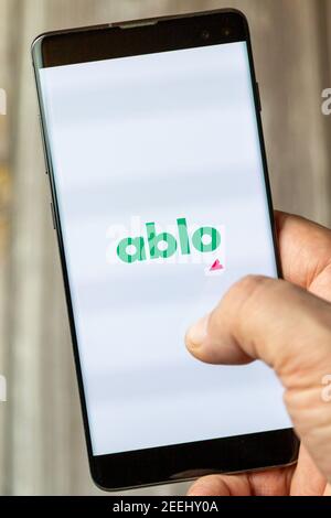 A mobile phone or cell phone being held in a hand with the ablo app open on screen Stock Photo