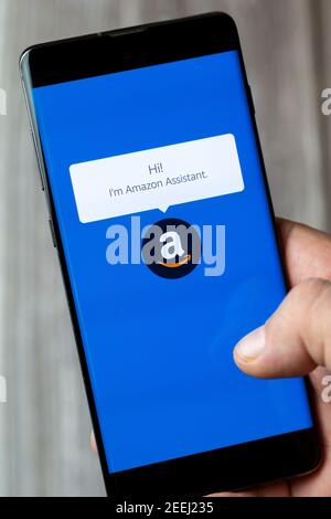 A mobile phone or cell phone being held in a hand with the Amazon assistant app open on screen Stock Photo