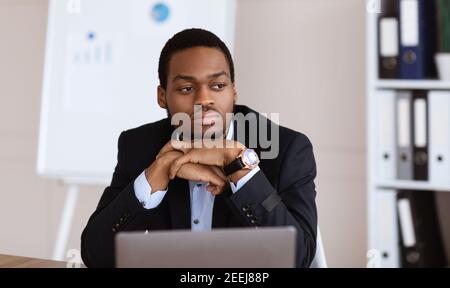 Upset african american businessman working with laptop in office Stock Photo