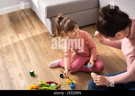 A mother and her daughter painting Easter eggs at home. Stock Photo