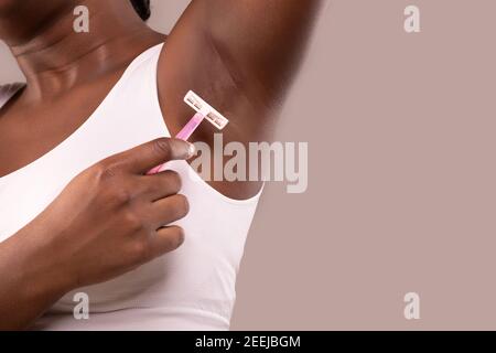 Hair Removal. Unrecognizable Black Woman Shaving Her Armpit With Pink Razor