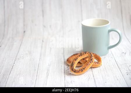A blue cup and delicious bagels on a light wooden background. Background with copy space Stock Photo