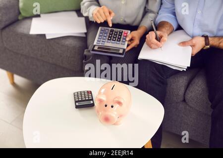 Couple sitting on sofa with papers and calculator, planning expenses and managing budget Stock Photo