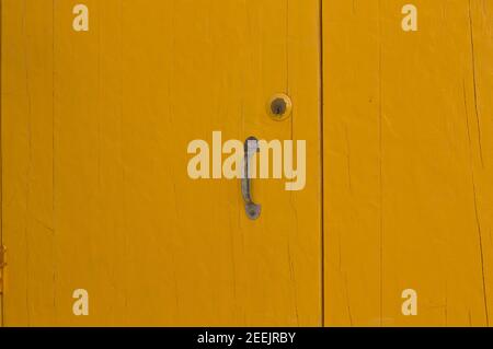 A yellow wooden door background with a rusted iron handle (Pesaro, Italy, Europe) Stock Photo