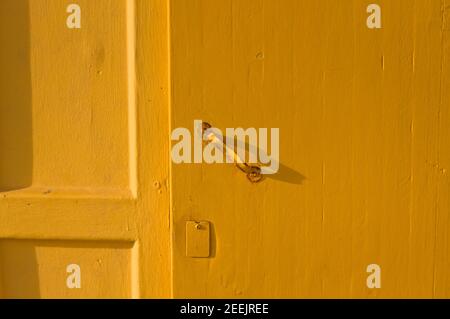 A yellow wooden door background with a rusted iron handle (Pesaro, Italy, Europe) Stock Photo