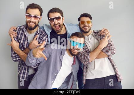 Group of young friends in sunglasses having fun and posing for funny photo in studio Stock Photo