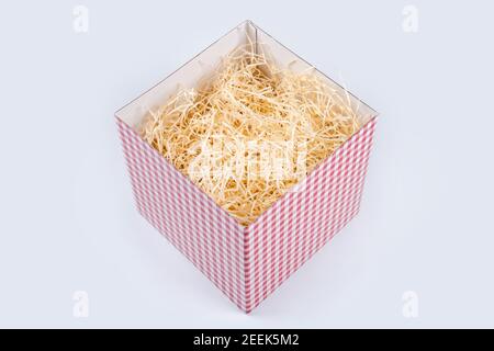 Opened gift box with decorative straw, filler, shavings. Top view, empty giftbox isolated on white, mockup for design. Stock Photo