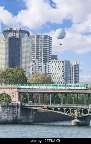 Subway train on the bridge over Seine river against skyscrapers with air balloon in Paris, France Stock Photo