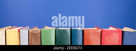 Simple composition of hardback books, raw books on a blue background. Stacking of books without inscriptions, empty spine. Back to school. Open book. Stock Photo