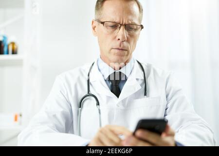 Serious male doctor using mobile phone at work Stock Photo