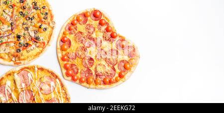 three different kinds of pizzas, around and heart shaped on white background with copy space, salami, mushrooms, tomaton, pepperoni, cherry tomato and Stock Photo