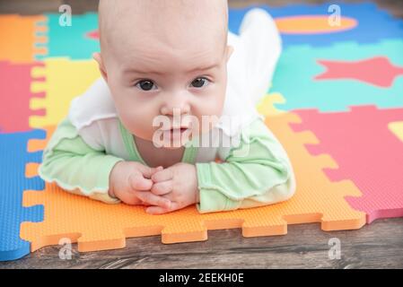 Laughing child on a colored rubber mat puzzle for playing foam eva with geometric figures Stock Photo