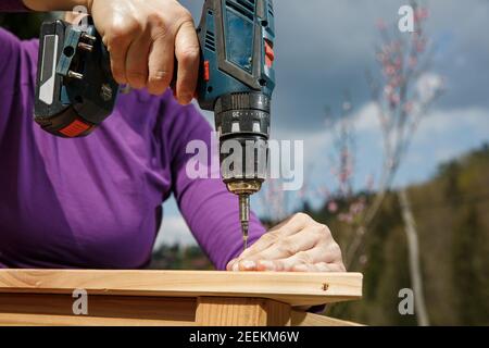 Woman screwing a wooden frame using power drill.  DIY concept. Powerful woman. Stock Photo