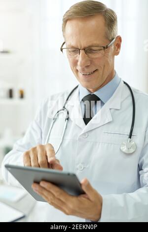 Cheerful male doctor using tablet computer in clinic Stock Photo