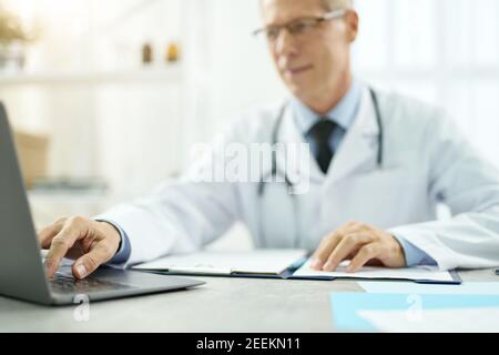 Handsome doctor using modern notebook in clinic Stock Photo