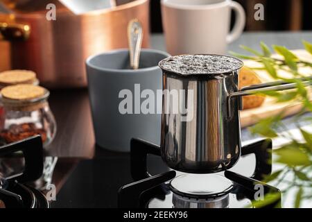 Brew coffee in a steel turk on a gas stove Stock Photo