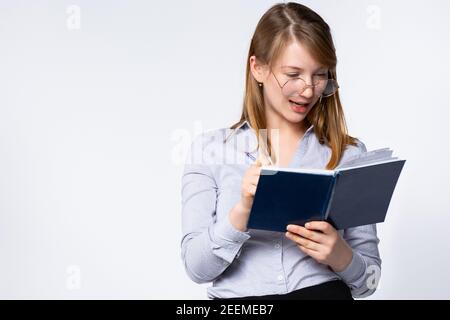 Portrait of beautiful young teacher looking into book on gray background, side space for text Stock Photo