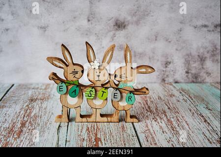Three wooden Easter bunnies with decoration and the text Easter written on eggs. Stock Photo