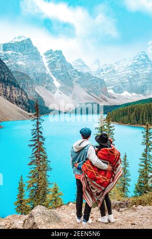 The beautiful Lake moraine at sunset, Beautiful turquoise waters of the Moraine lake with snow-covered rocky mountains in Banff National Park of Canada , couple visit the lake men and woman mid age Stock Photo
