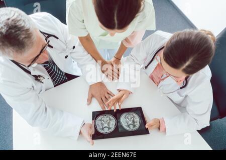 Team of doctors and nurses in meeting using a tablet computer Stock Photo