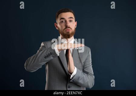 Young businessman calling for a timeout wearing a grey suit and black tie Stock Photo
