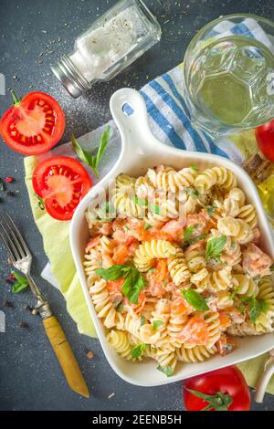 Spring diet healthy vegan pasta. Italian fusilli pasta with tomatoes, green vegetables, fresh herbs, cream cheese or feta, on dark table background co Stock Photo