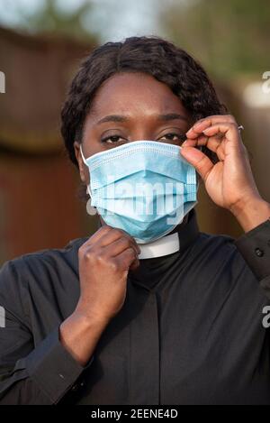 England, UK, December 2020. A black minister wearing a protective medical mask and white collar during Coronavirus outbreak Stock Photo