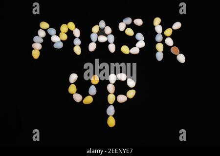 The words MASK UP spelled out using candy, chocolate eggs. Stock Photo