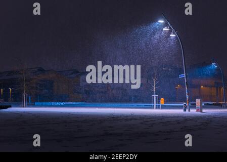 Snow flurries on a square in the evening, street lights and snow flurries, it snows in the evening on a large, illuminated square Stock Photo