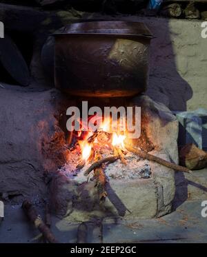 Water boiling over an earthen stove using wood sticks as fuel Stock Photo