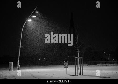 Snow flurries on a square in the evening, street lights and snow flurries, it snows in the evening on a large, illuminated square, black and white Stock Photo