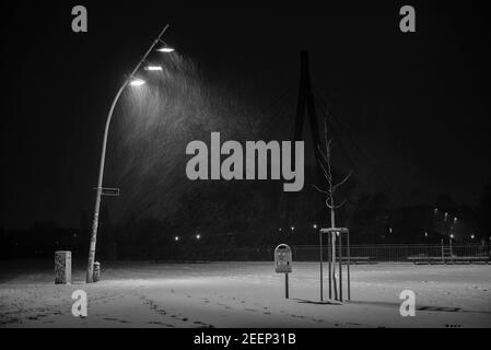 Snow flurries on a square in the evening, street lights and snow flurries, it snows in the evening on a large, illuminated square, black and white Stock Photo