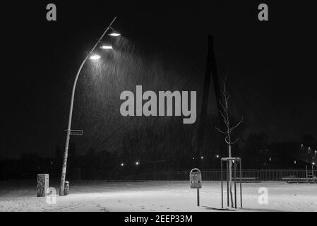 Snow flurries on a square in the evening, street lights and snow flurries, it snows in the evening on a large, illuminated square, black and white Stock Photo