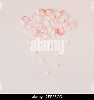 White and pink pastel cloud and rain made with rose  petals over beige background. Minimal nature creative concept. Stock Photo