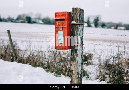 Traditional red English Postbox covered in snow in the countryside Stock Photo