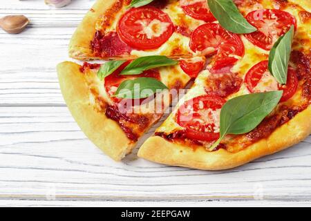 Pizza with cheese, tomatoes and basil on a white wooden table Stock Photo