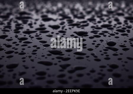 Droplets of water scattered on a shiny black surface Stock Photo
