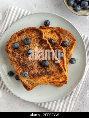 Close-up from above of three slices of french toast with blueberries on a plate on grey background, minimalistic style Stock Photo