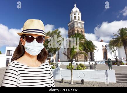 Travelling during the corona or covid pandemic: woman tourist wearing protective face mask, sunglasses and hat at Teguise, Lanzarote. Stock Photo