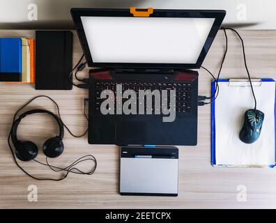 Flat lay of desk with laptop, notebook, powerbank, headphones and graphic tablet Stock Photo
