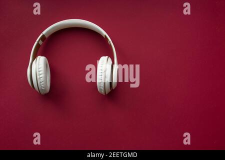 White wireless headphones on red background. Top view. Stock Photo