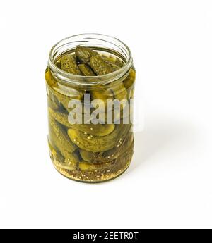 Delicious pickled cornichons in an open glass jar isolated on white background. Whole green gherkins marinated with dill and mustard seeds. Crunchy ba Stock Photo