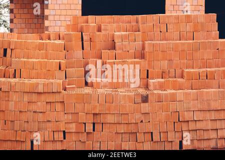 Clay brick building material and building under construction in the background. Stock Photo