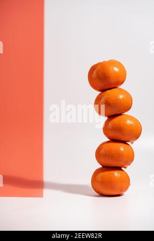 Stacked tangerines isolated on white and orange background. Healthy eating. Minimalism and balance concept with bright shadows Stock Photo