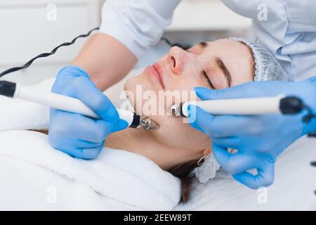 Close-up of electrodes of the microcurrent therapy apparatus on the face of a young beautiful girl. Stock Photo