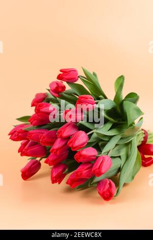 A large bouquet of red tulips lies on a delicate background - spring flowers for the holiday of March 8 or Valentines Day. A postcard Stock Photo